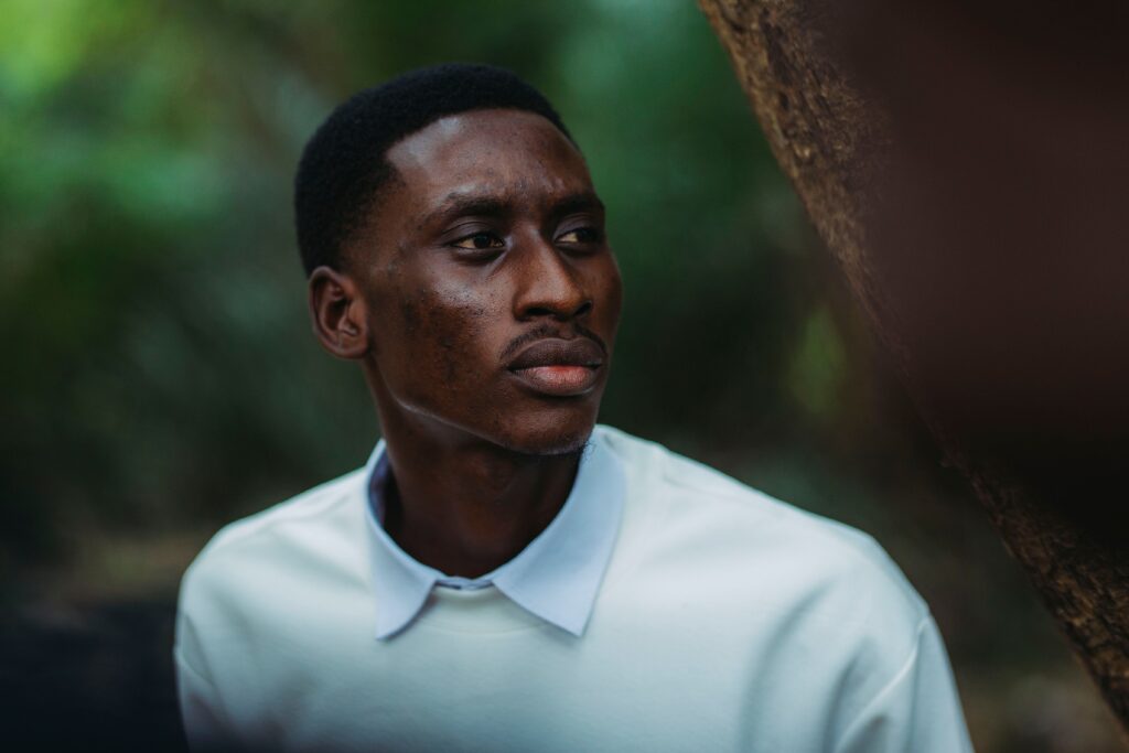 A serene portrait of a man deep in thought, captured outdoors with soft natural light.