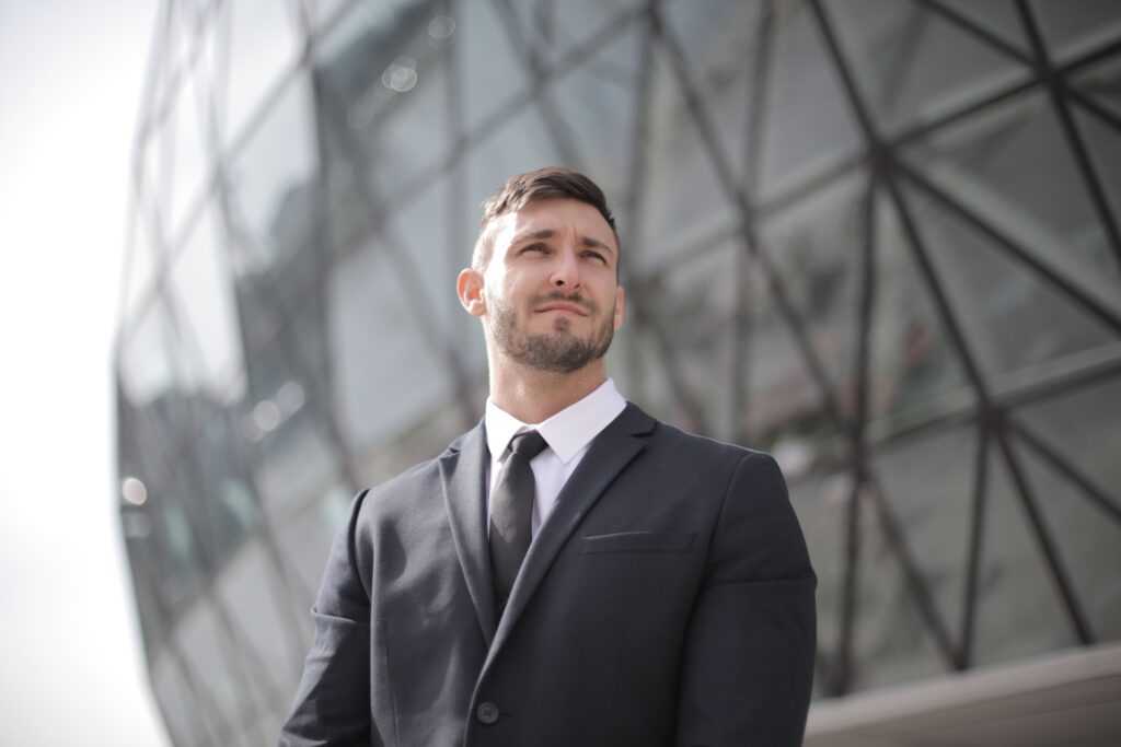 Portrait of a confident businessman in a suit standing outside a modern office building.